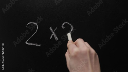 Two and two make four. Hand writing chalk blackboard school simple math addition two multiply two equals four. Inscription 2x2=4 simple mathematical equation board writing chalkboard education concept