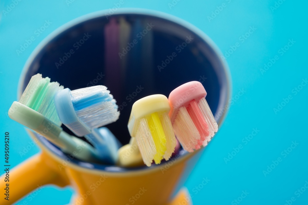 Close up colorful toothbrush in ceramic cup with copy pace in bathroom. Dental care concept.