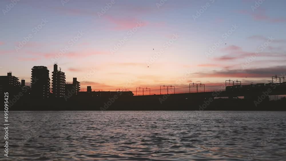 A beautiful sunset view of a train crossing a bridge over Tamagawa river in Tokyo, Japan A beautiful sunset view of a train crossing a bridge over Tamagawa river in Tokyo, Japan
