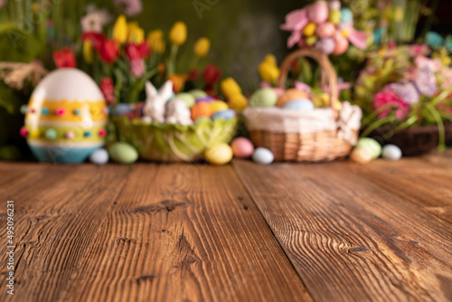 Easter time. Easter decorations on the rustic wooden table. Easter bunny, easter eggs in basket and cabbage leaf. Bouquets of spring flowers. 
