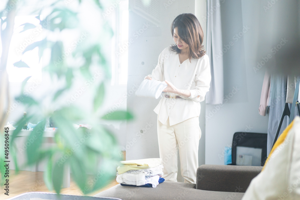 自宅で洗濯物をたたむ若い女性 自宅で洗濯物をたたむ若い女性