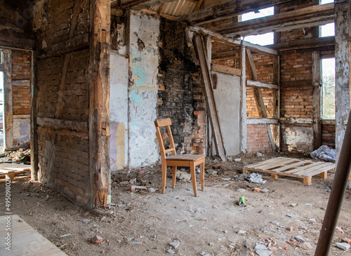 Ein alter Holzstuhl steht in einem zerfallenem Bauernhauses Ruine Lost Place 