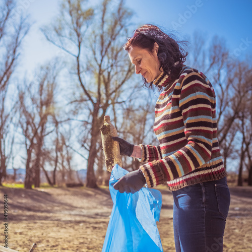 woman putting plastic bottle into blue garbage bag