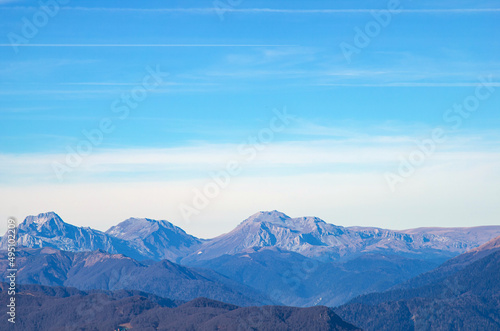 Beautiful landscape in the mountains with peaks against the blue sky and valleys covered with grass