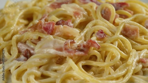 carbonara spaghetti with cream on a white plate, rotation shot
