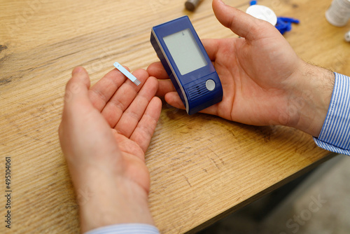 Close up photo a man holding glucometer and stripes in his hands for checking blood sugar level, diabetes concept.