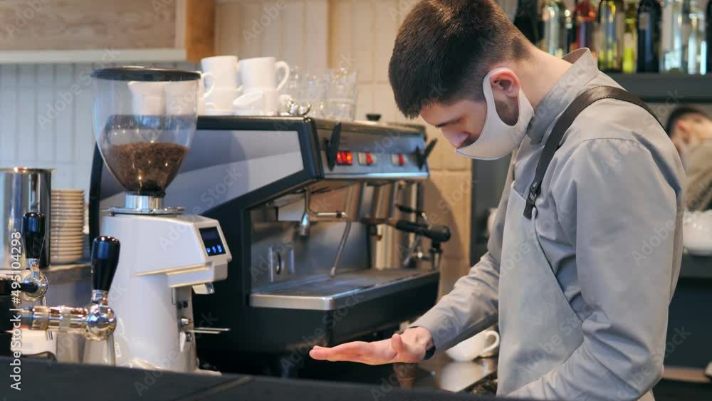 A barista making coffee, cappuccino with an espresso machine in a cafe, restaurant. A professional bartender wears a face mask.The service sector.The concept of a coffee shop in a specialized cafe A barista making coffee, cappuccino with an espresso machine in a cafe, restaurant. A professional bartender wears a face mask.The service sector.The concept of a coffee shop in a specialized cafe
