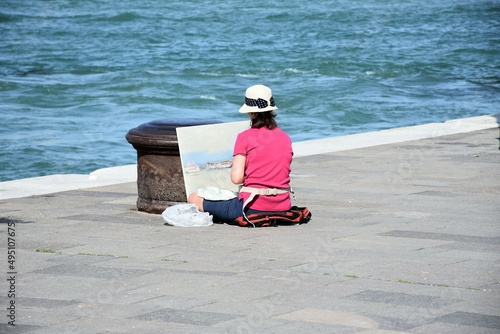 Pittrice disegna in riva alla laguna di venezia