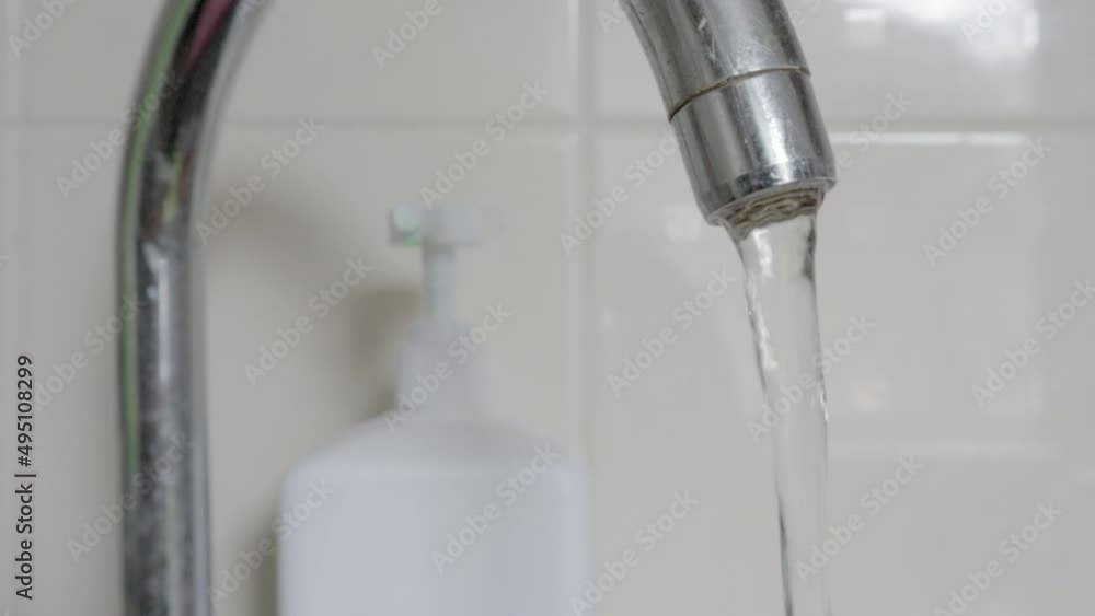 Close-up of drinking tap water flowing from a faucet. Designing a faucet in the kitchen or bathroom. The concept of water saving and water consumption, tariff and price of water. Close-up of drinking tap water flowing from a faucet. Designing a faucet in the kitchen or bathroom. The concept of water saving and water consumption, tariff and price of water.