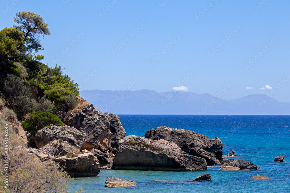 rocks into the sea near Zaga beach in Koroni, a coastal town in Messenia, Peloponnese,Greece.  Sunny day with blue sky