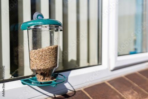 A bird feeder outside the window that allows people in the house to watch birds feeding through the window