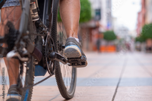Close up on casual woman's legs while running her electro bicycle in urban street