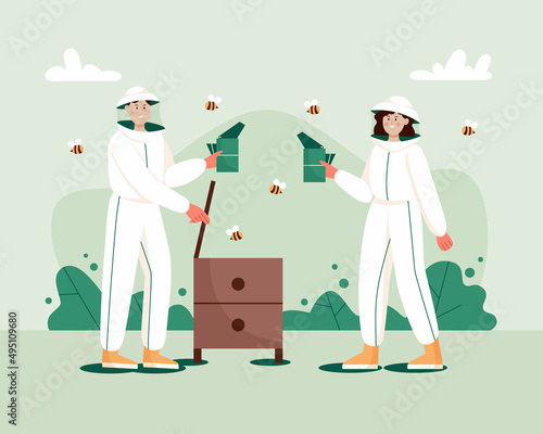 Man and woman in hat and protective uniform with a bee smoker device and beehive. Beekeeping workers in uniforms.