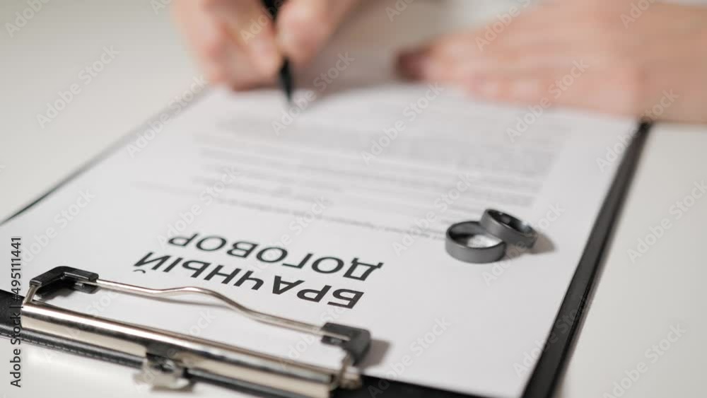 prenuptial agreement in Russian-speaking countries. Woman's hand signs documents. Premarital agreement of bride and groom in office of lawyer. prenuptial agreement in Russian-speaking countries. Woman's hand signs documents. Premarital agreement of bride and groom in office of lawyer.