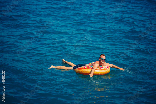 A man floats on an inflatable ring in the sea with blue water. Vacation at the sea on a sunny day. Turkey vacation concept