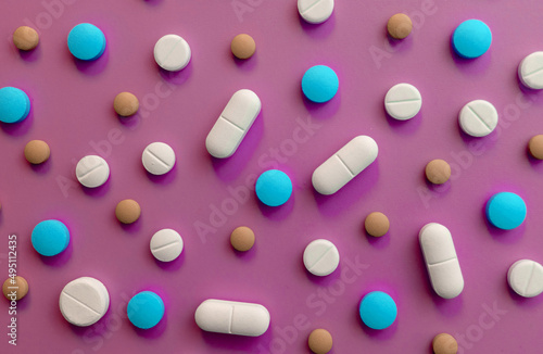 Colored pills, tablets on a pink background