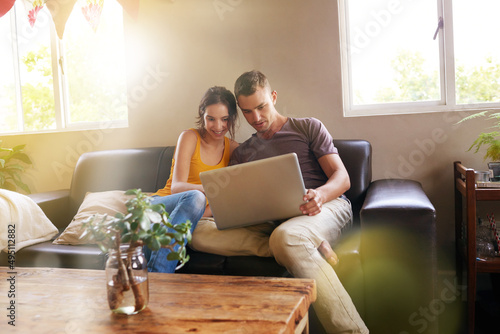 Home is where the hotspot is. Shot of a happy young couple using a laptop together on the sofa at home.