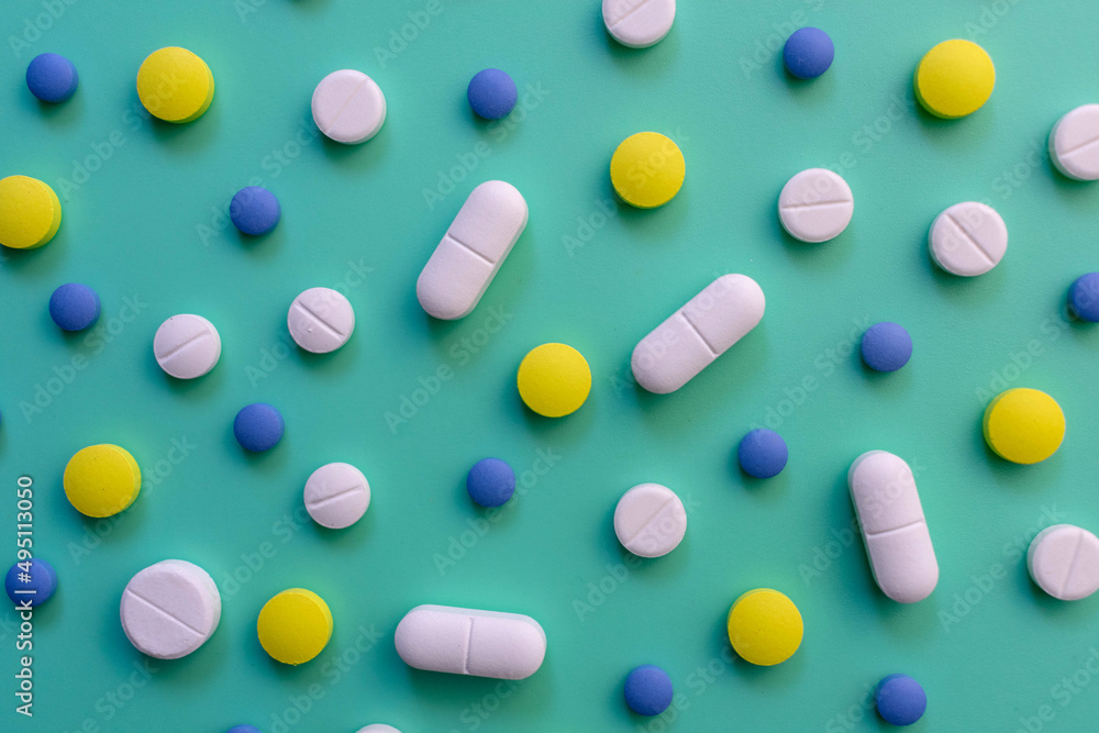 Background of multi-colored pills on a green background.