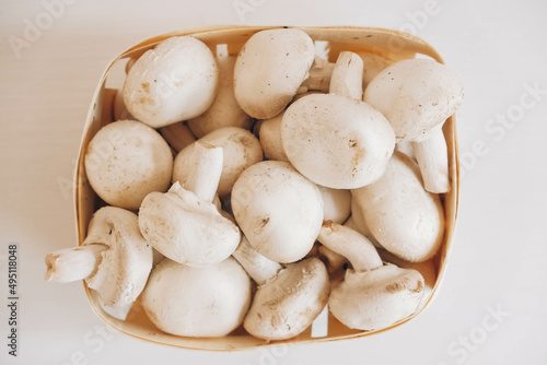 Champignon mushrooms in a wicker basket on a white background