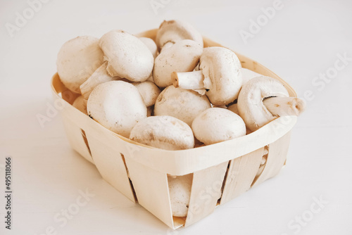 Champignon mushrooms in a wicker basket on a white background