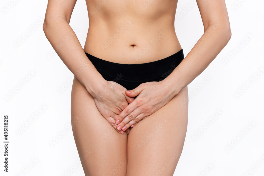 Cropped shot of a young woman in black panties holding her crotch with her hands, suffering from cystitis isolated on white background. Gynecological problems, genital tract infections. Healthcare