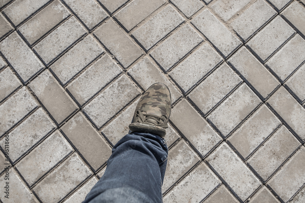 Man's leg in autumn shoes on paving slabs