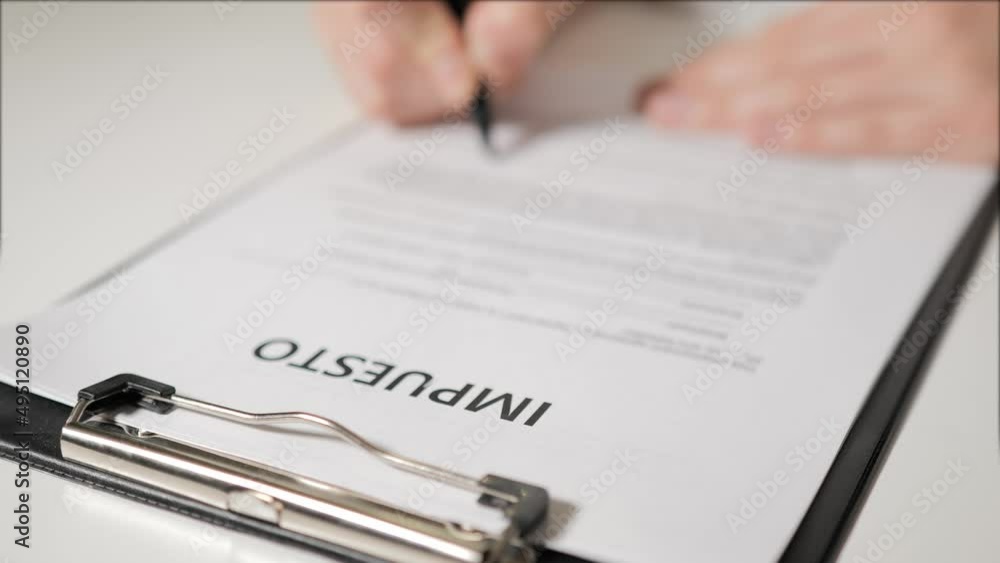 taxes in Spanish-speaking languages. Man's hand signs a tax return. Tax individuals and legal entities. Budgeting. Accounting for expenses and income. taxes in Spanish-speaking languages. Man's hand signs a tax return. Tax individuals and legal entities. Budgeting. Accounting for expenses and income.