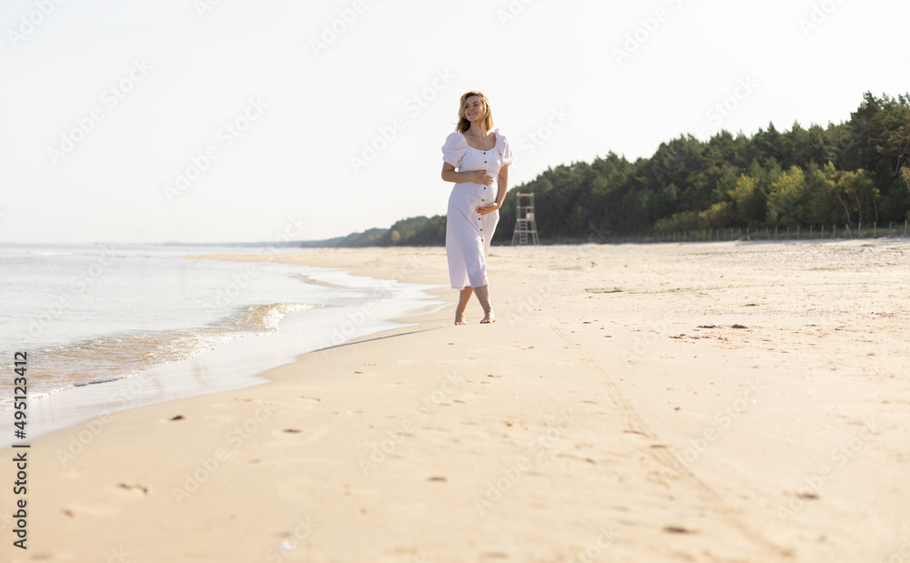 Happy pregnant woman spending time on a beach