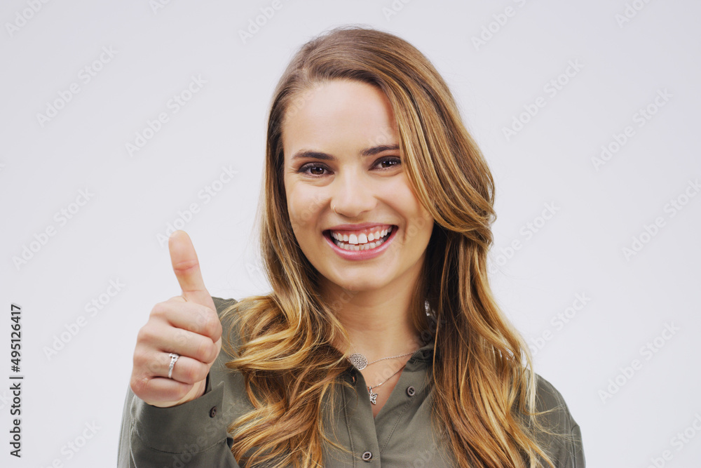 I approve. Studio portrait of an attractive young woman giving a thumbs up against a grey background. I approve. Studio portrait of an attractive young woman giving a thumbs up against a grey background.