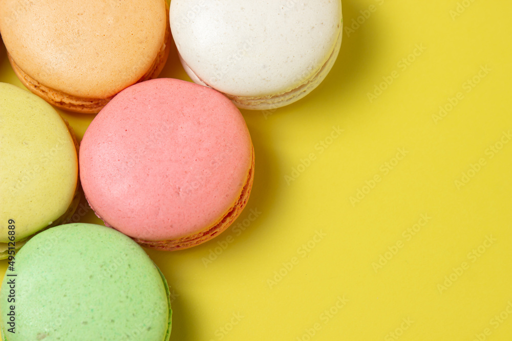 Colored macarons on a yellow background. Light and tasty dessert. traditional dessert Colored macarons on a yellow background. Light and tasty dessert. traditional dessert