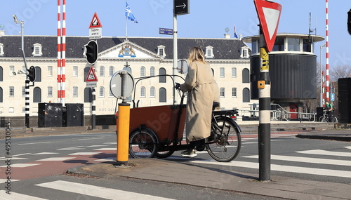 Amsterdam Prins Hendrikkade Street View with Woman on a Cargo Bike, Maritime Museum Facade and Kortjewantsbrug Bridge, Netherlands photo
