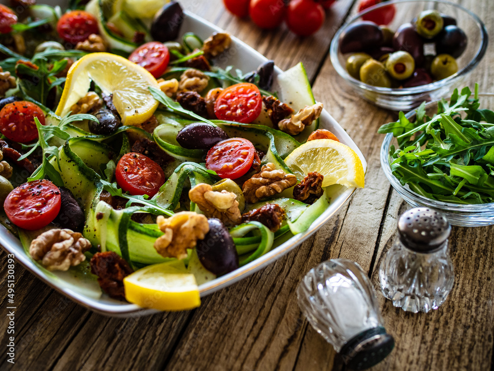 Fresh vegetable salad - lettuce, cherry tomatoes, cucumber, walnuts, lemon, black and green olives and arugula on wooden table
Fresh vegetable salad - lettuce, cherry tomatoes, cucumber, walnuts, lemon, black and green olives and arugula on wooden table