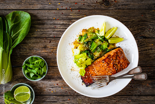 Foto Fried teriyaki salmon steak with pak choi and lime on wooden table