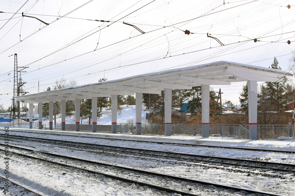 Empty railway track and empty passenger platform, winter landscape.