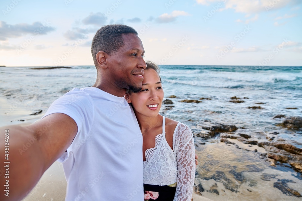 Happy couple in love taking selfie together on smartphone, on beach