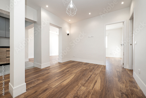 living room with open kitchen and several entrances to different rooms with dark wooden floors and freshly painted walls