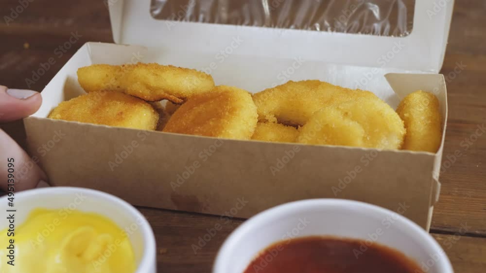 Hands are taken from the delivery box and the nuggets are dipped in the sauce. Medium plan Hands are taken from the delivery box and the nuggets are dipped in the sauce. Medium plan