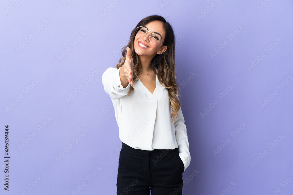 Young caucasian woman isolated on purple background shaking hands for closing a good deal Young caucasian woman isolated on purple background shaking hands for closing a good deal