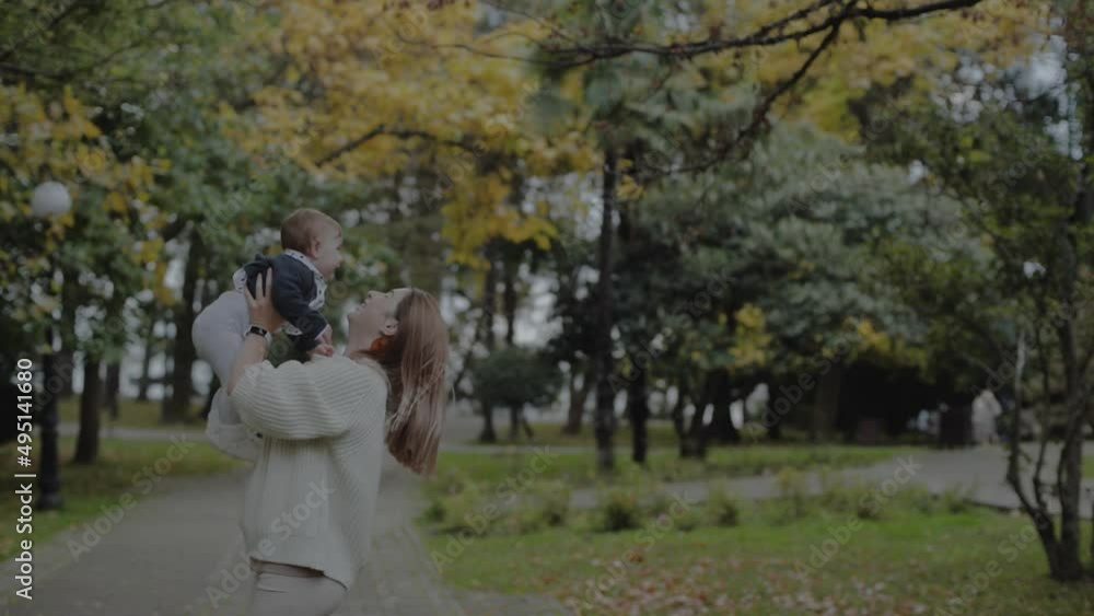 A young mom walks in the park with a baby and a stroller. They sit on a bench and play. Autumn A young mom walks in the park with a baby and a stroller. They sit on a bench and play. Autumn