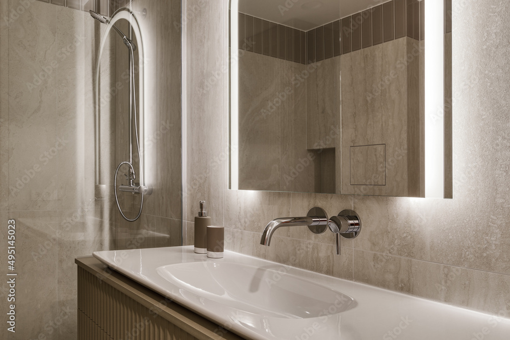 Modern minimalist bathroom interior design with marble stone tiles, arch mirror with led lighting and khaki furniture