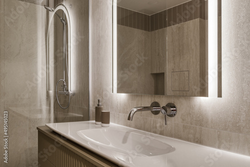 Modern minimalist bathroom interior design with marble stone tiles, arch mirror with led lighting and khaki furniture © Jevgenija Zukova