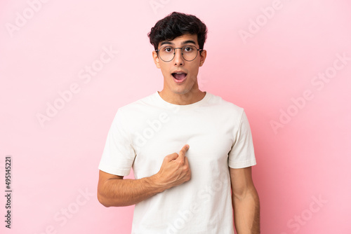 Young Argentinian man isolated on pink background pointing to oneself