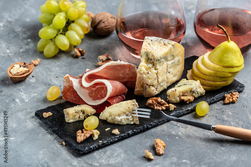 Romantic dinner with wine and assorted Cheese Plate with fruit. Grapes Pear Nuts Cashew Cheese with mold Gorgonzola. A glass of wine with cheese. Beverage