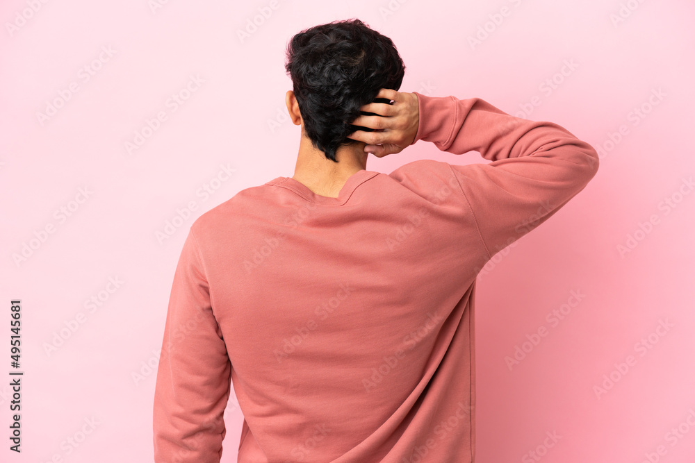 Young Argentinian man isolated on pink background in back position and thinking Young Argentinian man isolated on pink background in back position and thinking