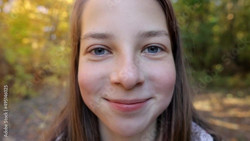 a large portrait of a funny and cheerful teenage girl in an autumn forest, a girl looking at the camera, human emotions