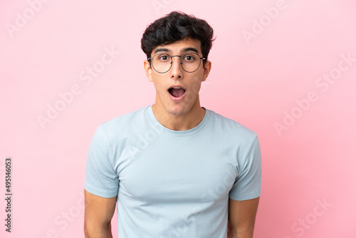 Young Argentinian man isolated on pink background With glasses and surprised expression