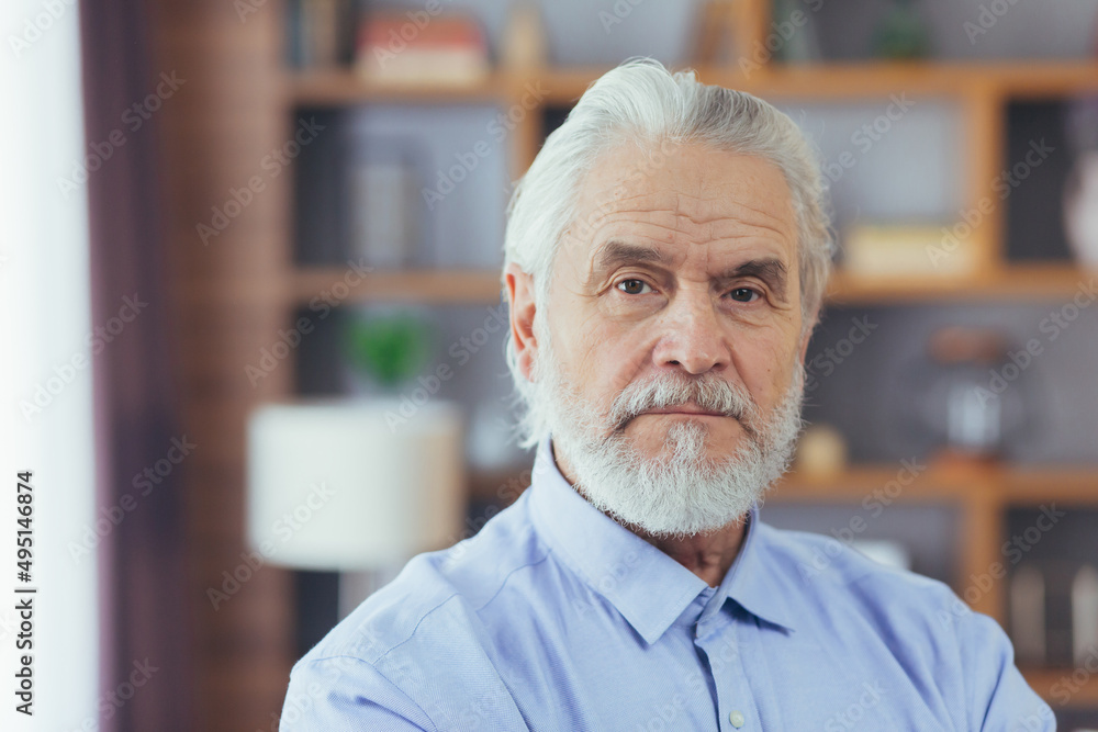 Close-up photo of portrait of old man at home, looking at camera and smiling Close-up photo of portrait of old man at home, looking at camera and smiling