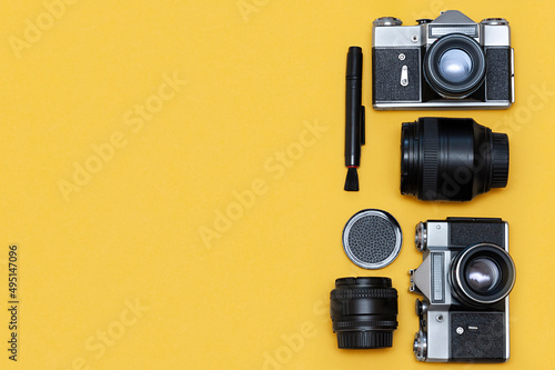 Cameras, lenses and accessories on a yellow background, top view. copy space