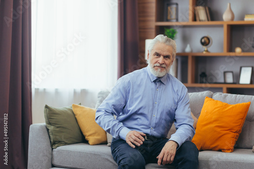 Serious for pensive grandfather man sitting on sofa at home