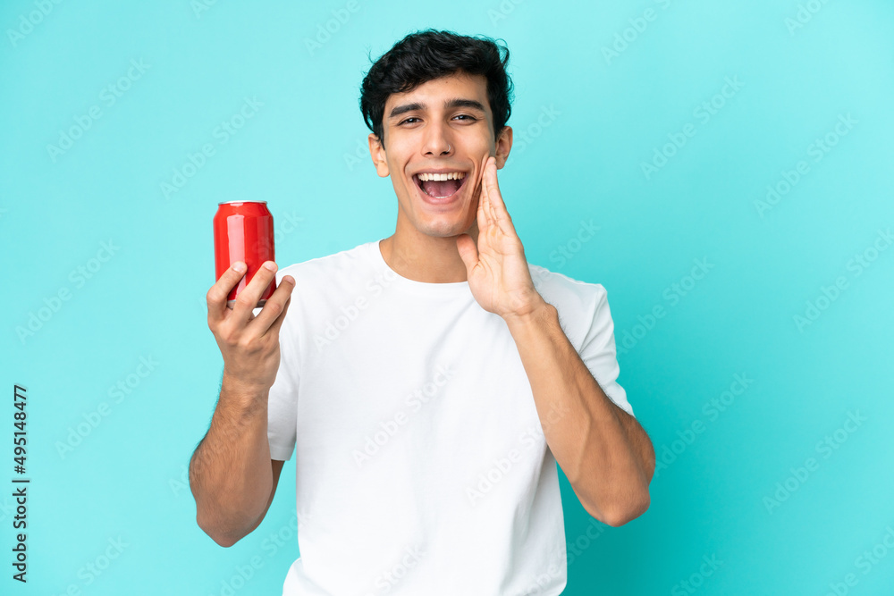 Young Argentinian man holding a refreshment isolated on blue background shouting with mouth wide open